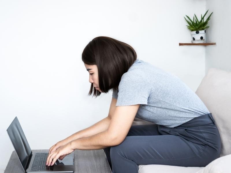 A Melhor Cadeira para Coluna Lombar: Guia Científico para Proteção da Saúde Postural 3 Uma pessoa sentada em uma cadeira para a coluna com péssima ergonomia.