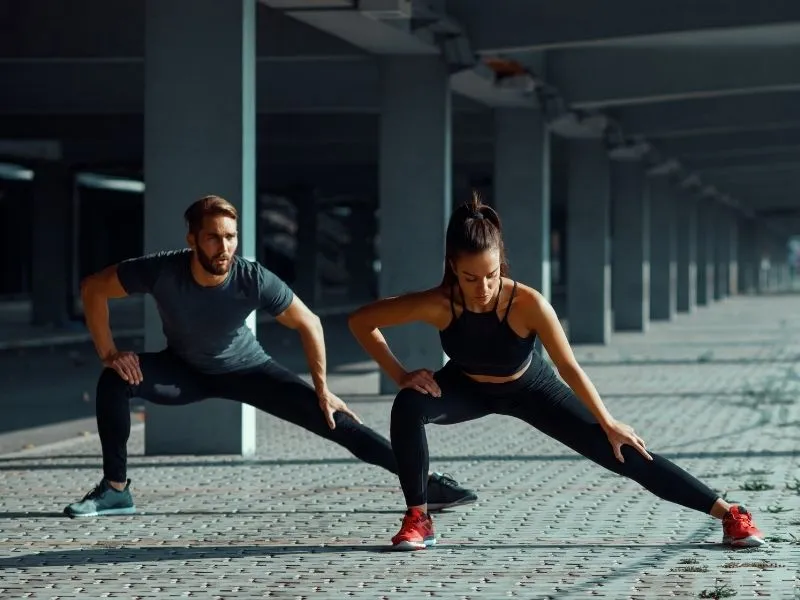 Alongamento Antes ou Depois do Treino: Guia 2025 2 Um casal fazendo alongamento pós treino